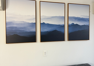 Three framed pictures professionally mounted in a straight row on the wall