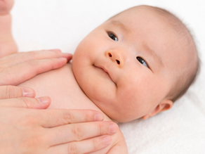 Baby lying on white blanket, receiving gentle massage. Baby looks content. "Louisville Prenatal Massage" text with tree logo in corner.