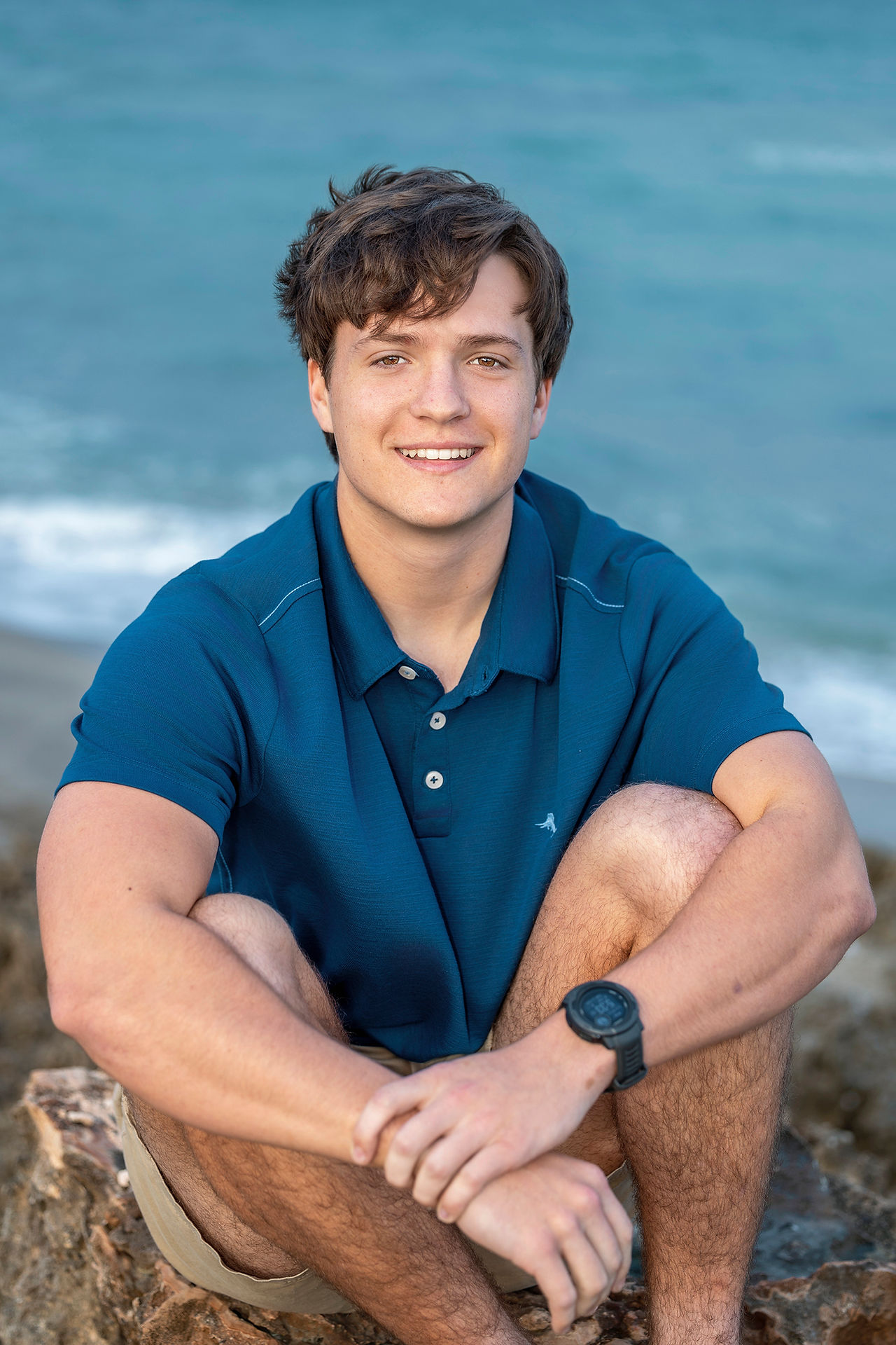 Morgan Williams sitting on the rocks at Ross Witham Beach for his Martin County senior photos