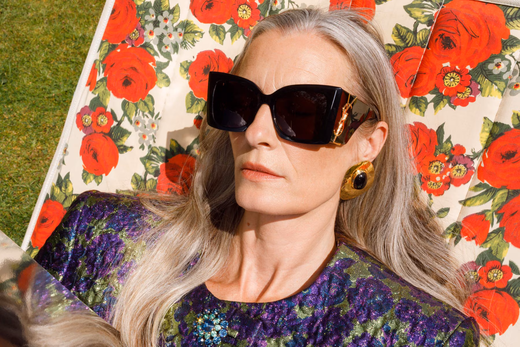 A Saint Laurent lady sunbathing on a floral lawn chair with a mirror for tan reflection 