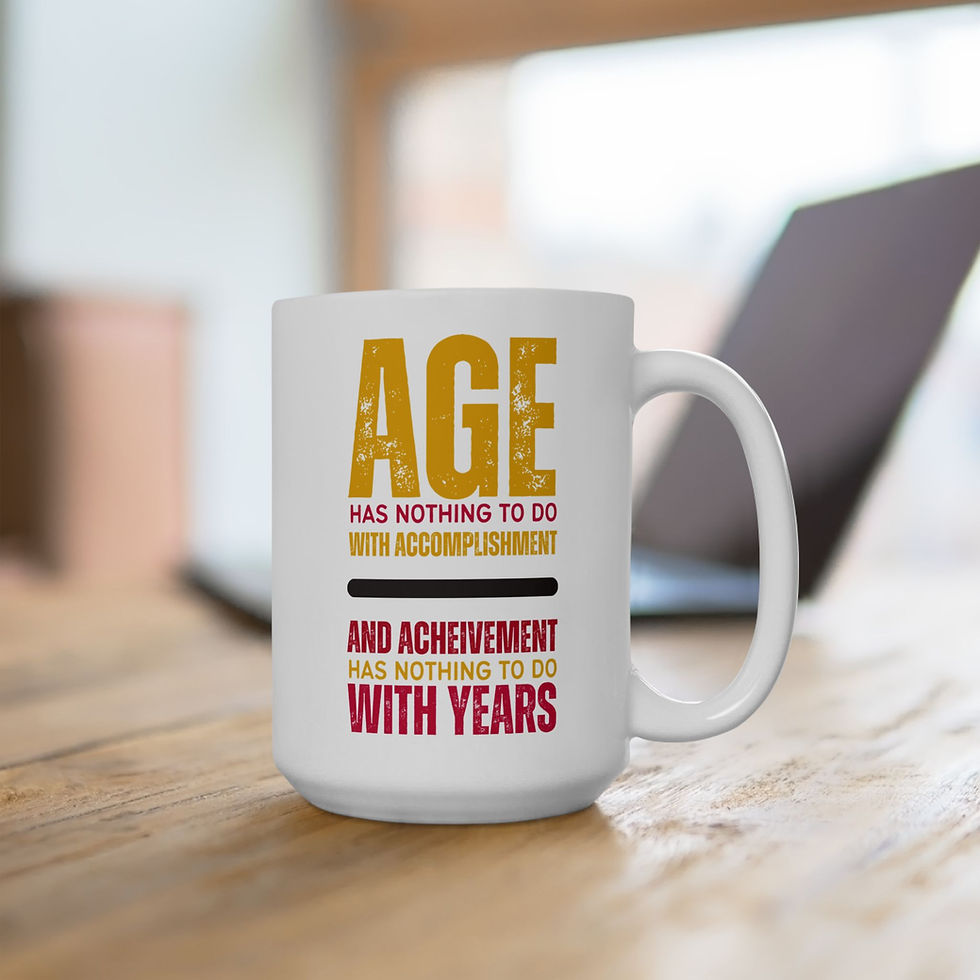 White mug on wooden table with text: "Age has nothing to do with accomplishment and achievement has nothing to do with years." Blurred laptop in background.