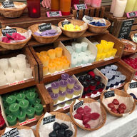 Colorful candles arranged in baskets at Toledo Farmers' Market for sale.