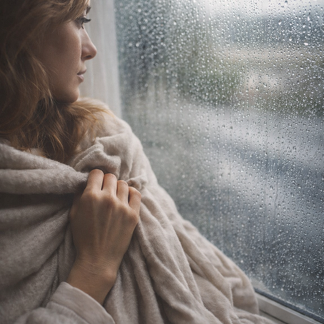 Frau schaut nachdenklich aus dem Fenster