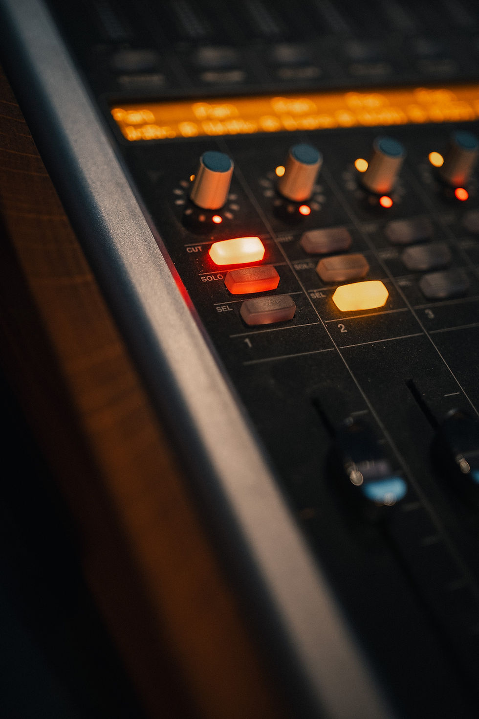 Gros plan sur une console de mixage éclairée aux Linster Studios, utilisée pour la production audio professionnelle.