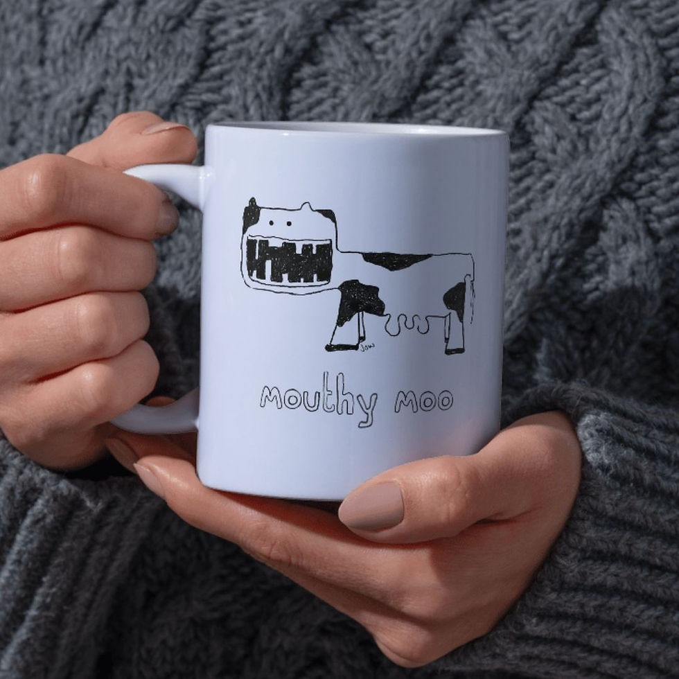 Hands holding white mug with 'mouthy moo' cow design