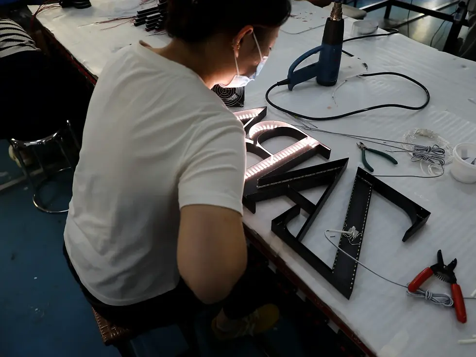 Worker assembling LED lighting inside custom metal channel letters