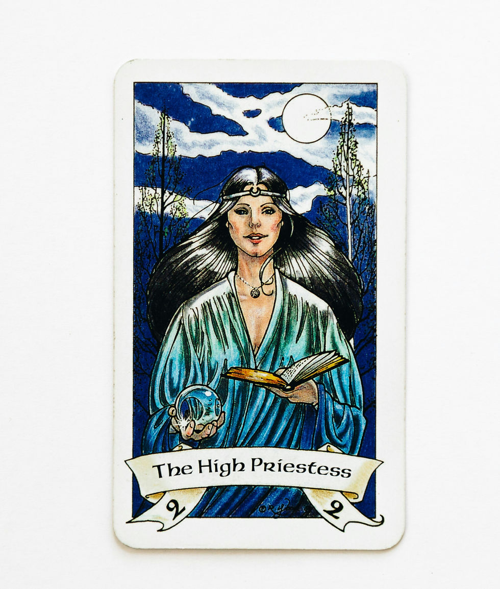 Tarot card The High Priestess shows a woman in blue robes holding a book and crystal ball beneath a moonlit sky.