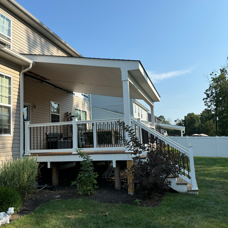 Custom elevated deck addition with white vinyl railing, black balusters, and landscaped yard by Booth Home Impressions in South Jersey