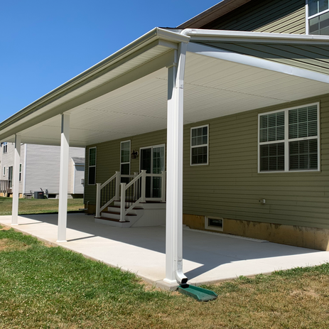 Custom covered patio addition with white vinyl posts, attached roof structure, concrete pad, and stair access by Booth Home Impressions in South Jersey