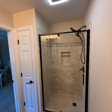 Bathroom addition converted from walk-in closet featuring matte black framed glass shower, neutral tile surround, decorative mosaic border, and built-in niche in South Jersey