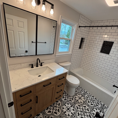 Bathroom remodel with wood tone vanity, white quartz countertop, matte black fixtures, subway tile tub surround, and patterned encaustic floor tile in South Jersey