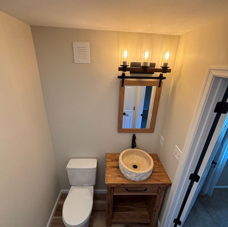 Powder room remodel with rustic wood vanity, stone vessel sink, wood frame mirror, industrial light fixture, and matte black hardware by Booth Home Impressions in South Jersey