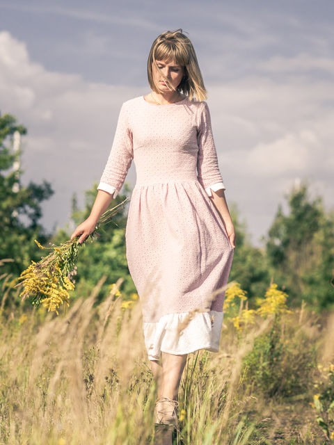 Eine Frau in einem rosé farbenen Kleid in der Natur.