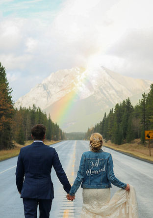 A couple walking towards a rainbow after their wedding in the mountains