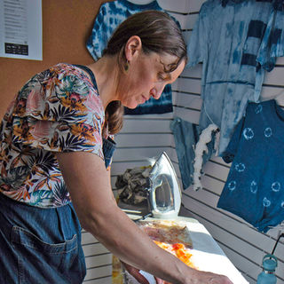 Carey Stoudt ironing a botanical printed fabric.