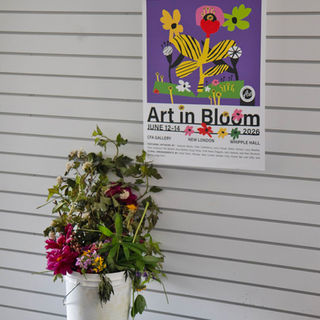 Art in Bloom poster displayed above a bucket of flowers.