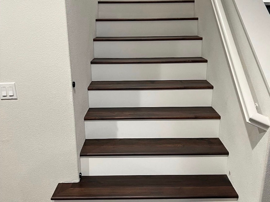 Staircase with dark wood treads and white risers by Coastal Flooring.