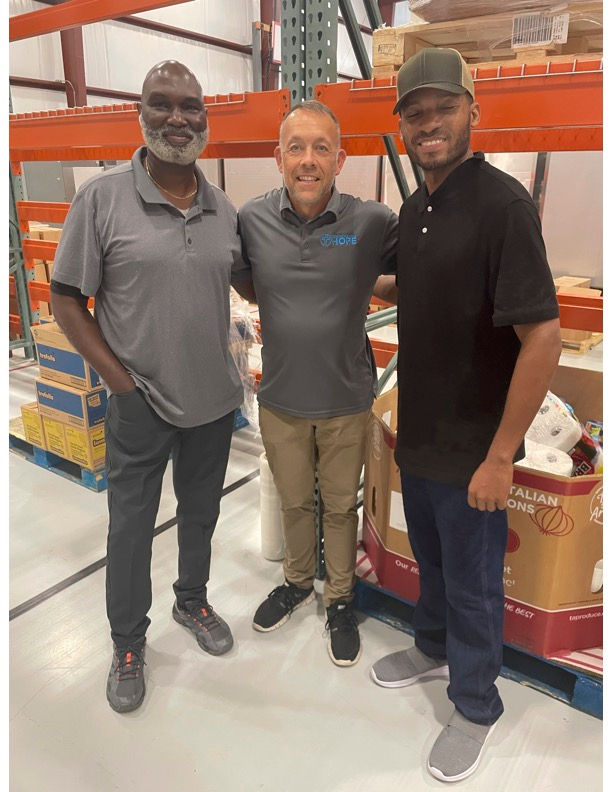 Three men smiling in a warehouse