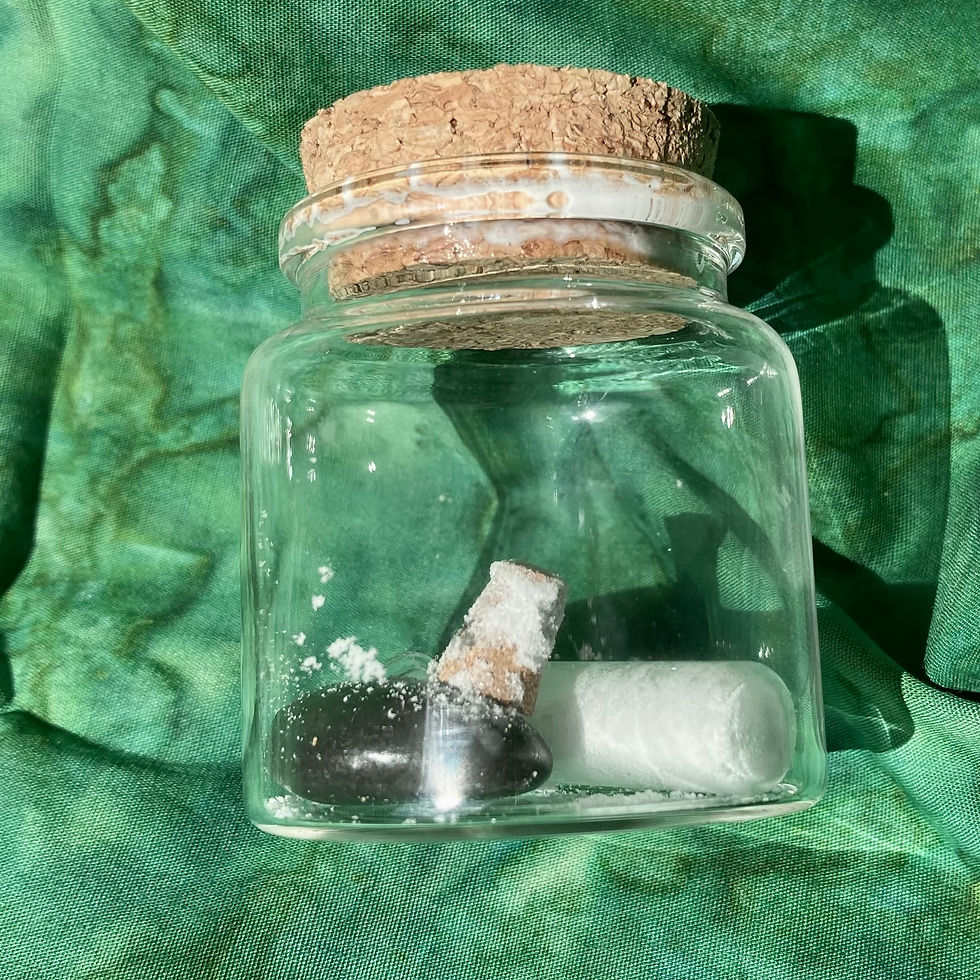 Small glass jar with cork top, containing stone and vial with white powder