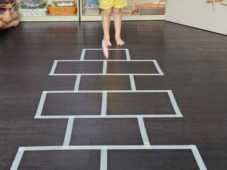 A girl plays hopscotch indoors during class activity.