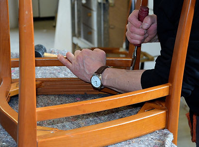 Holzstuhl verkehrt herum auf einem Tisch, der Stuhl wird repariert