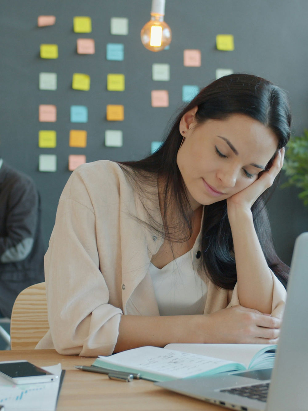 A person sitting at a desk with a laptop, shoulders relaxed, eyes softly closed, one hand resting open on the keyboard.