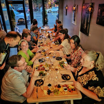 Guests eating at a long table dinner and drinking wine.