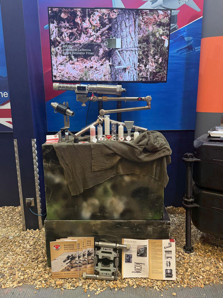 A small exhibition display of counter explosive ordnance equipment, with a TV behind showing the kit in action against live explosive ordnance.