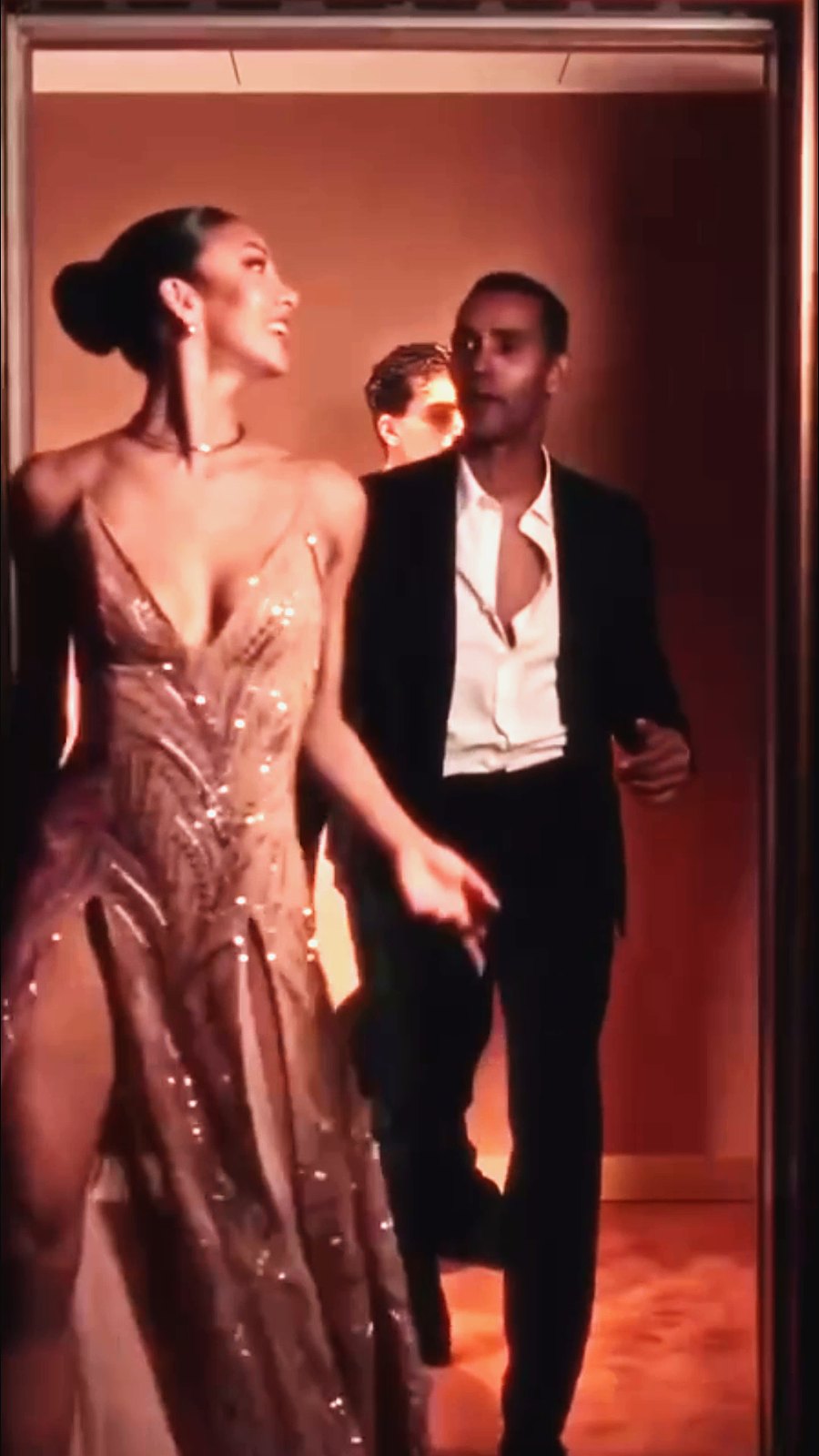 Guests in evening wear inside a bronze elevator