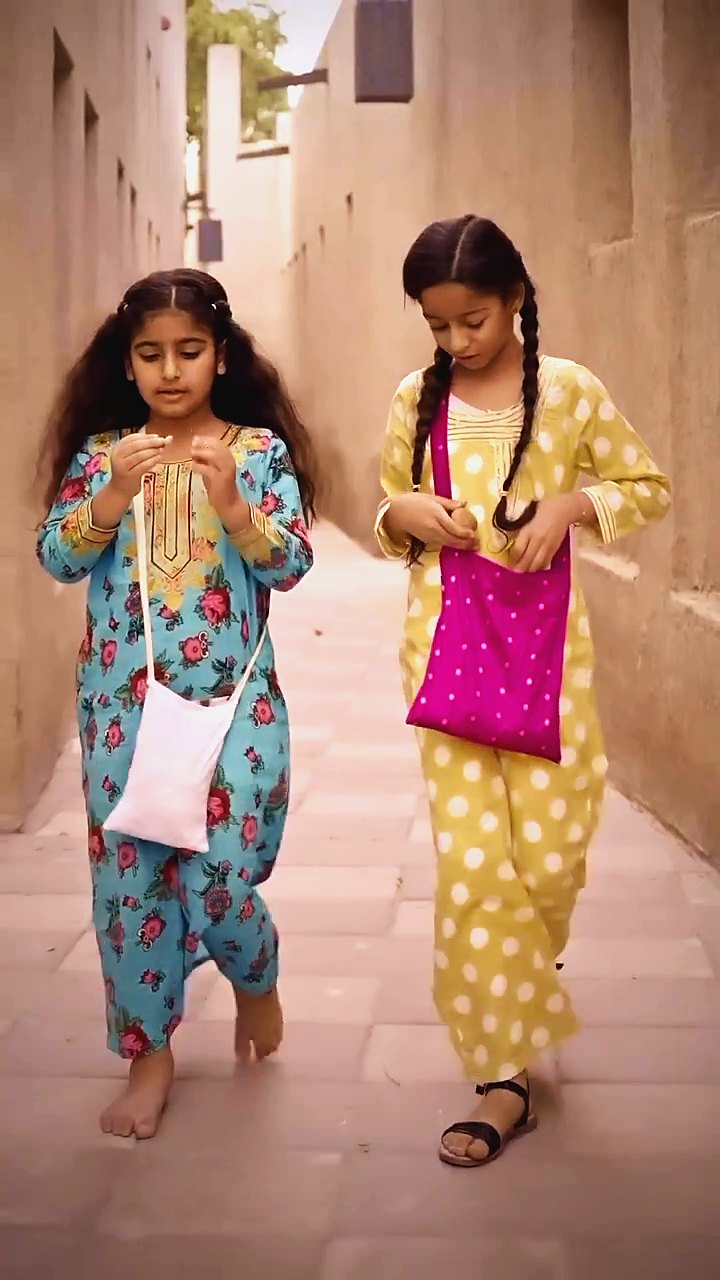 Children in traditional dress running through Al Shindagha's old lanes
