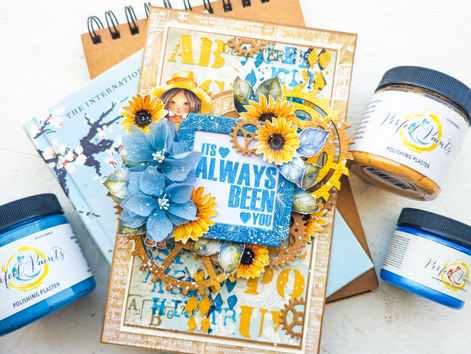 Decorative card with "It's Always Been You" text, featuring blue flowers and yellow sunflowers. Set on notebooks with blue and yellow Perfect Paints.