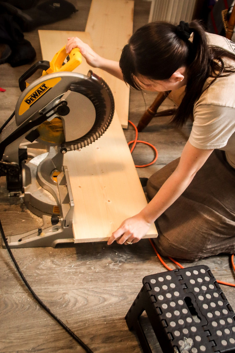 a woodworker cutting a wood board at the mitre saw