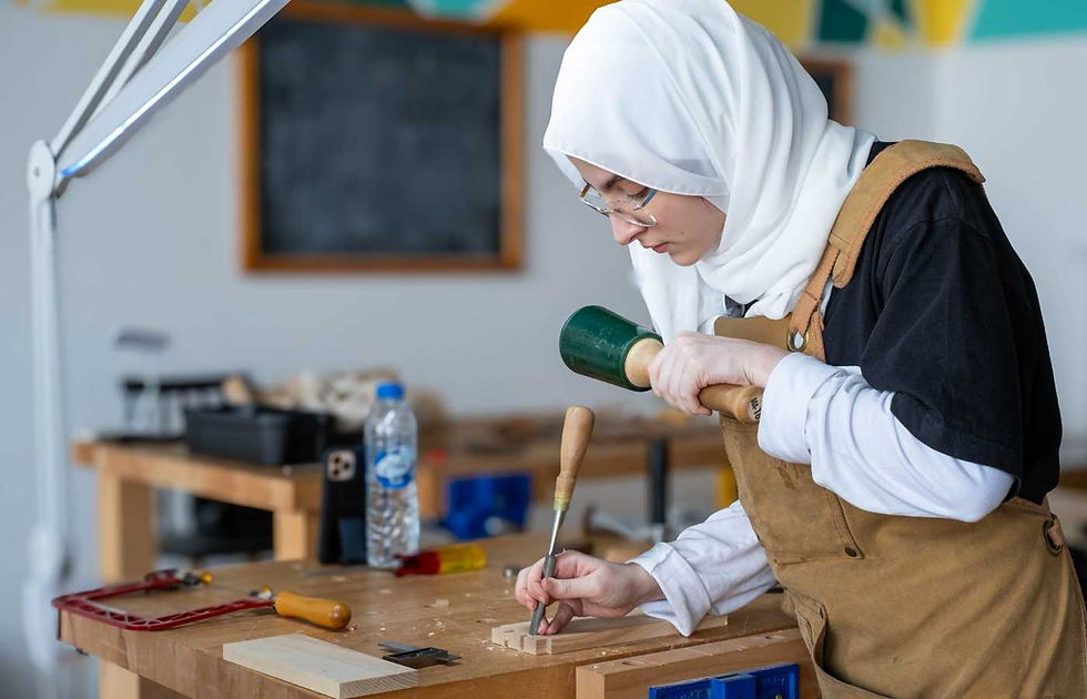 Young woman in hijab using chisel and mallet during a woodworking class at The Makers Society in Dubai
