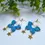 Thumbnail: Whimsical butterfly-shaped statement earrings in vibrant blue polymer clay with star charms, gold hoops and posts