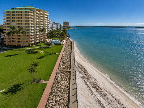 High-rise building by a seawall and sandy beach. Built By Collier Seawall and Dock LLC.