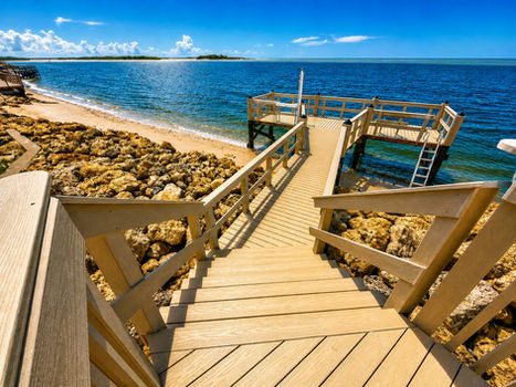 Pier with composite decking over riprap leading to the water. Proudly built by Collier Seawall and Dock LLC.