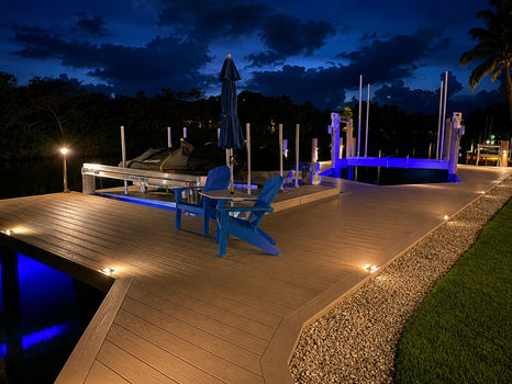 Illuminated boat lift and dock with blue LED lighting at night. Lift Installed By Collier Seawall and Dock LLC.