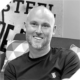 Professional Business Man in black and white, smiling directly at the camera.