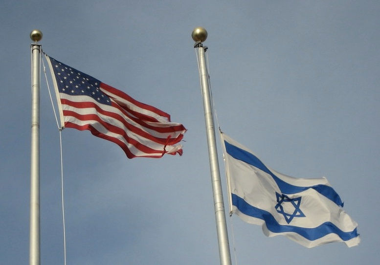 American and Israeli flags waving with blue sky in back