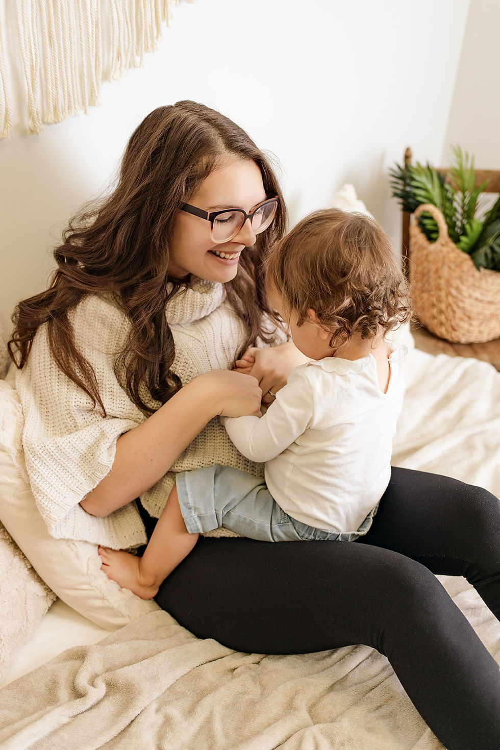 Pregnant mother holds her toddler on her lap and smiles