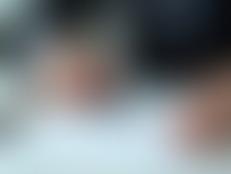 A person in a suit signs a document with a black pen on a desk. Background is blurred, conveying a professional setting.