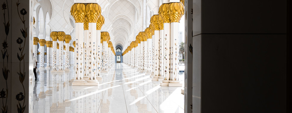 Couloir intérieur avec alignement de colonnes et jeux de lumière dans la mosquée.