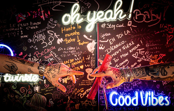 Deux mains tatouées se transmettent des outils de coiffure, symbole de savoir-faire et de passion. Collection "Transmission"