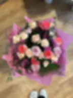 Un bouquet de roses roses pâles et corail, d'œillets bicolores roses et violets, et de petites fleurs violettes.