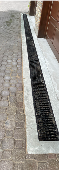 Linear drain installed on cobblestone driveway near garage door