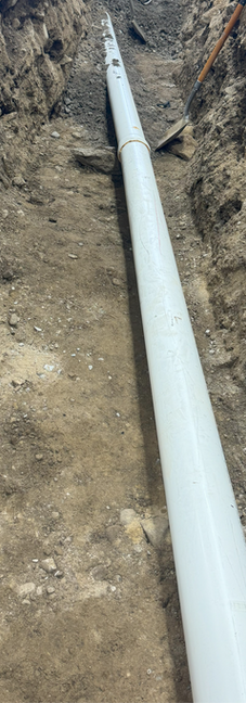 PVC pipe positioned in trench before grate installation.