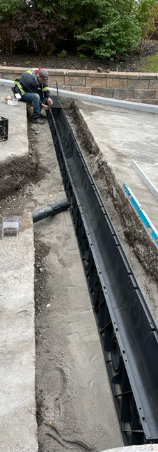 Installation of long drainage grate with team working on site.