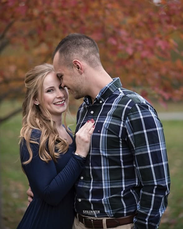 Smiling woman embraced by man in autumn leaves