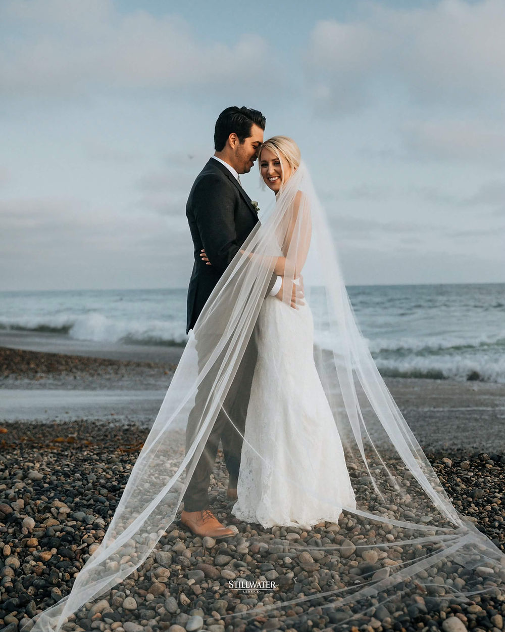 Bride and groom on beach with long veil