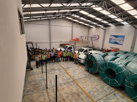 Equipo de trabajo en almacén industrial con bobinas de cable.